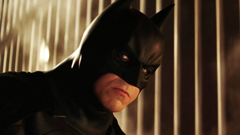 Christian Bale's Batman looks off into the distance in Batman Begins