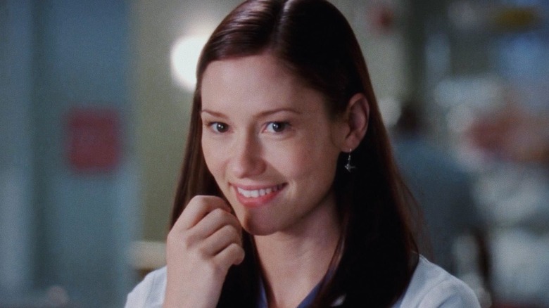 Lexie smiling with her hand near her face on Grey's Anatomy