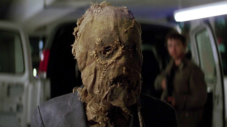 Jonathan Crane wearing his Scarecrow mask in front of a van in The Dark Knight
