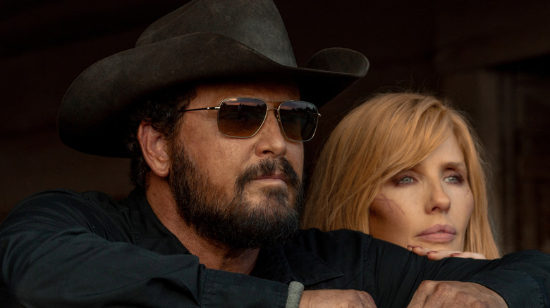 Cole Hauser's Rip Wheeler looks off into the distance wearing shades next to Kelly Reilly's Beth Dutton in Dutton Ranch