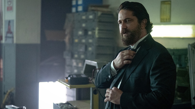 Big Nick O'Brien fixes his tie in Den of Thieves 2: Pantera