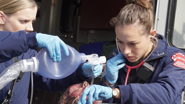 Jessica Chilton van Dora Madison verleent zorg aan een patiënt samen met Sylvie Brett van Kara Killmer in Chicago Fire