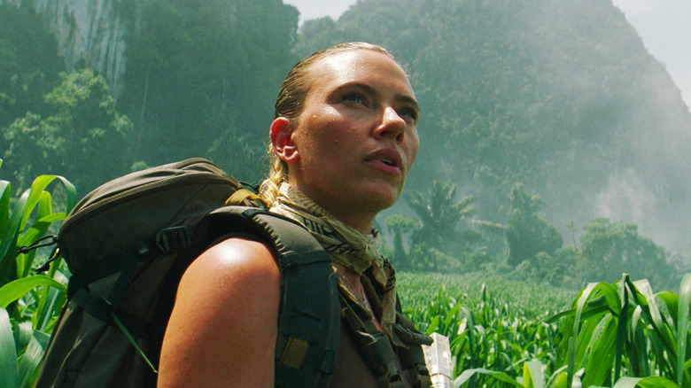Scarlett Ingrid Johansson's Zora Bennett looks up as she stands among plants in a field in Jurassic World: Rebirth