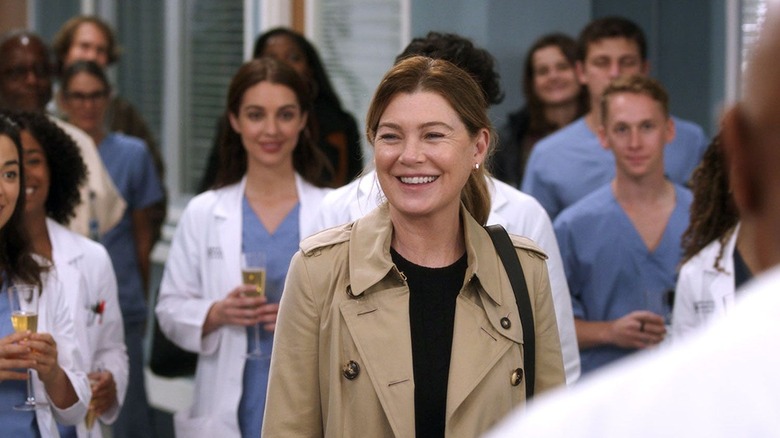Meredith smiling surrounded by coworkers on Grey's Anatomy