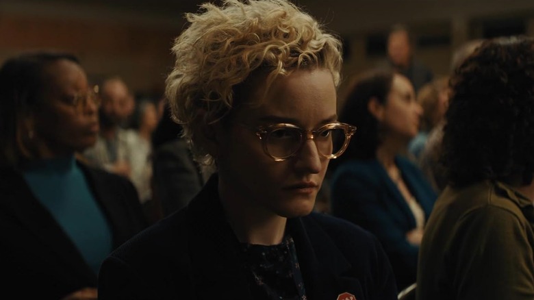 Justine lost in thought at a town meeting in Weapons