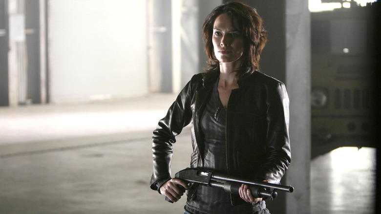 Sarah Connor holding a shotgun in a warehouse with a truck in the background in The Sarah Connor Chronicles