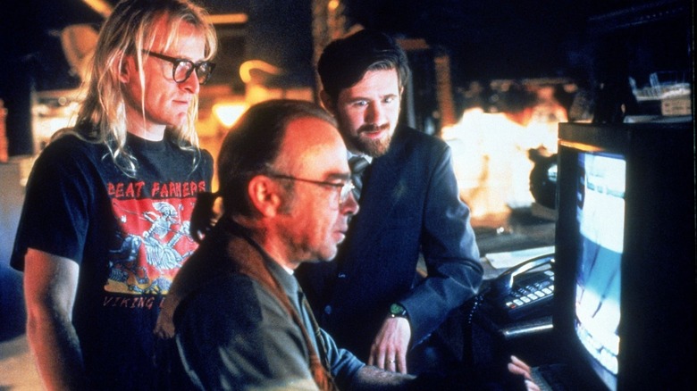 Langley, Frohike, and Byers in front of a computer, with Frohike at the keyboard, in their basement hideout. A scene from The Lone Gunmen.