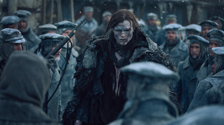 Jacob Elordi as Frankenstein walking through the soliders in the snow in Frankenstein (2025)