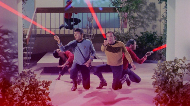 A group of Starfleet officers, all firing their phasers at giant amoeba creatures on the walls. A scene from Star Trek.