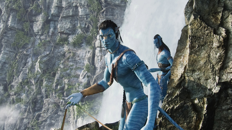 Jake Sully, in his Na'Vi body, standing on a cliff face in Avatar
