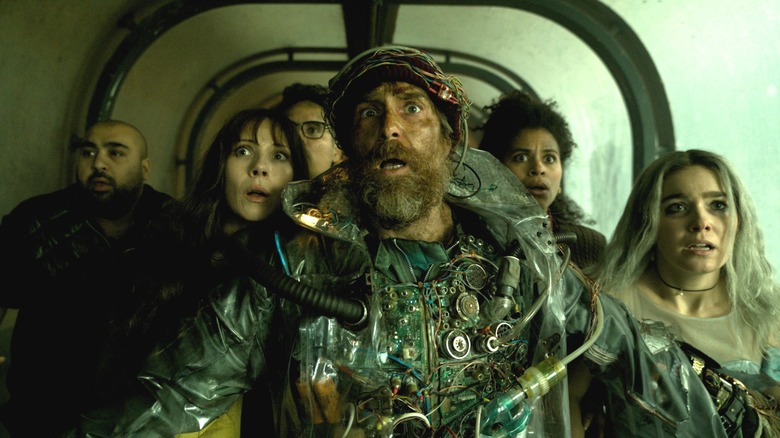 Asim Chaudhry as Scott, Juno Temple as Susan, Michael Peña as Mark, Sam Rockwell as the man from the future, Zazie Beetz as Janet, and Haley Lu Richardson as Ingrid standing in a narrow corridor in Good Luck, Have Fun, Don't Die