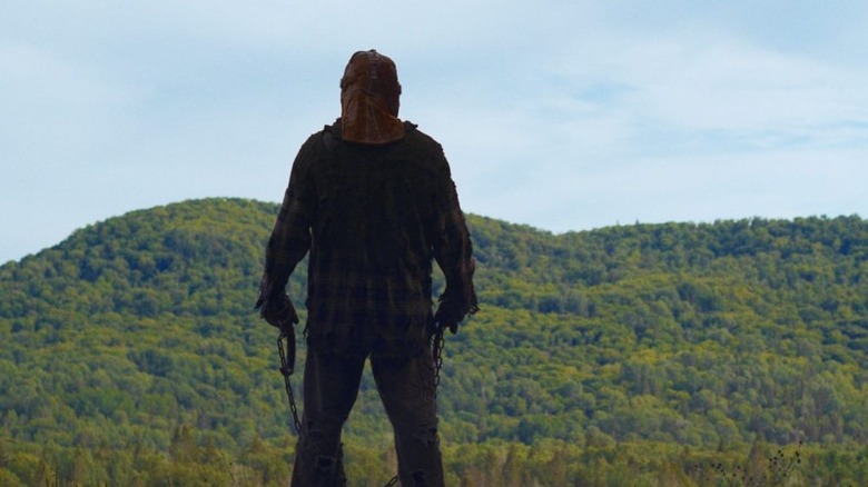 Johnny (Ry Barrett), masked, grabs a chain and a hook in the film In a Violent Nature (2024)