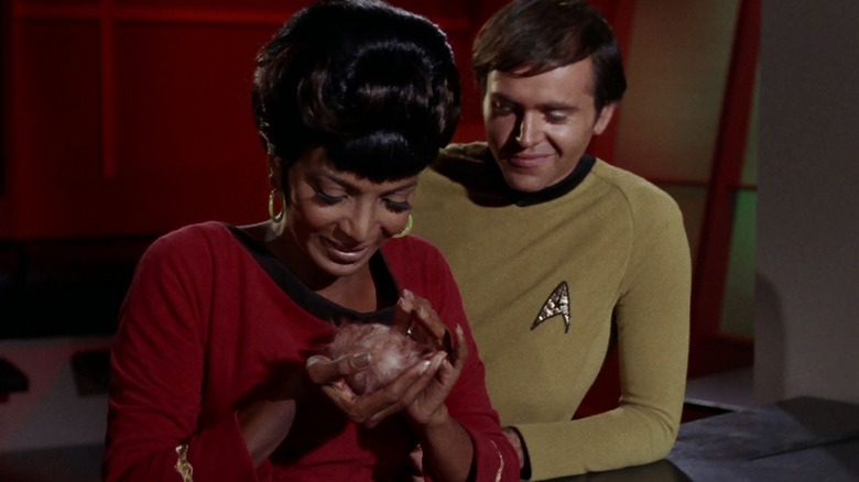 Uhura holding a tribble with Chekov looking on on Star Trek