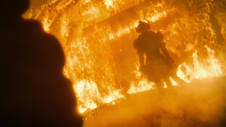 Bill Skarsgård's Pennywise stands amid a fire in It Welcome to Derry