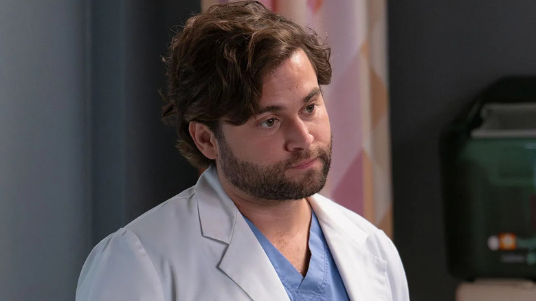 Levi in his white coat looking at a patient on Grey's Anatomy