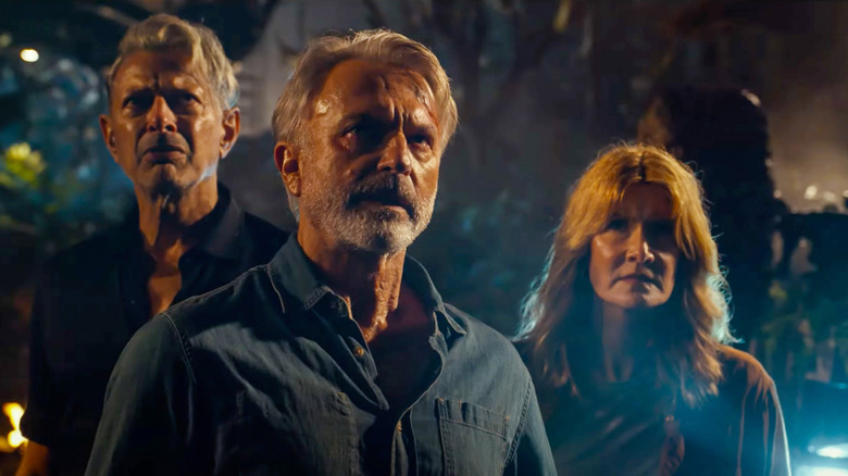 Ian Malcolm, Ellie Sattler, and Alan Grant standing in the jungle in Jurassic World Dominion