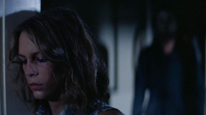 Laurie, tired, with Michael Myers standing behind her in Halloween (1978)