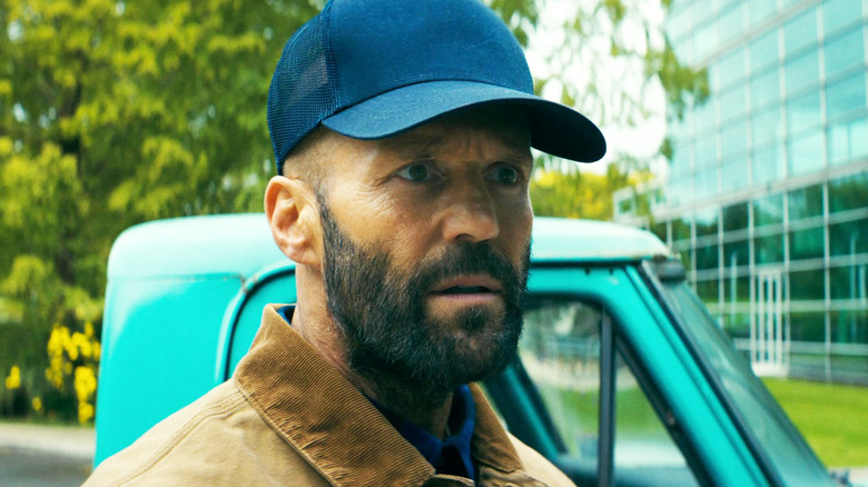 Jason Statham's Adam Clay looks intense standing by a car in The Beekeeper.jpg