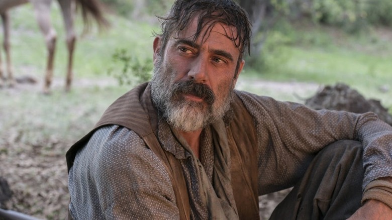 A bearded, dirt-covered Deaf Smith (Jeffery Dean Morgan) sits outdoors, looking pensively off to the left side with his arm resting on his bent knee in Texas Rising