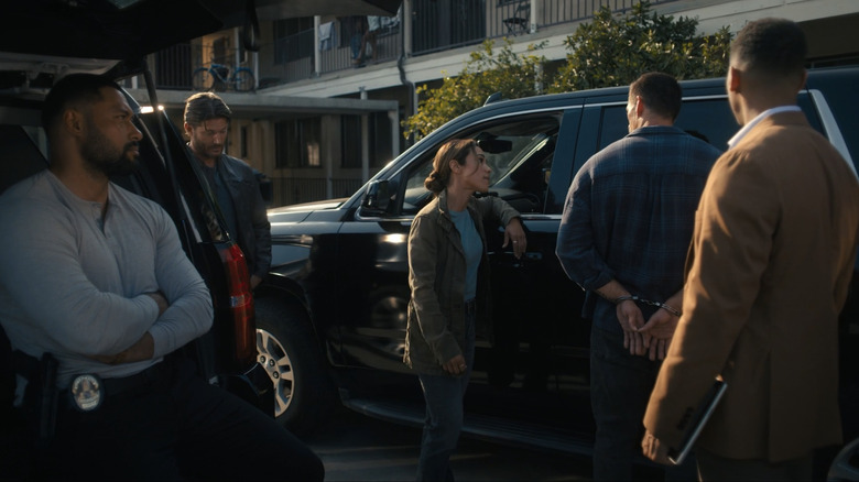 Jensen Ackles's Mark Mitchum poses with Jessica Camacho's Amber Oliveras as they arrest a criminal while Oli Latukfu's Luke Finau sits out front in the parking lot of Countdown