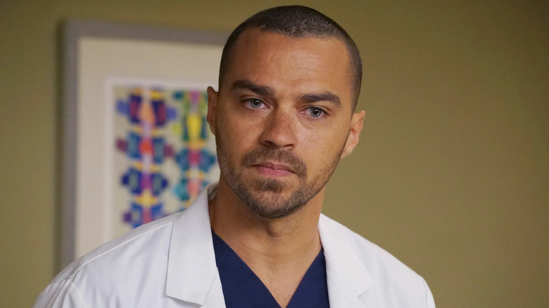 Jackson in a white coat in a patient room looking at someone on Grey's Anatomy