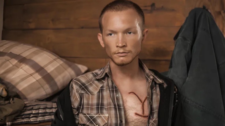 Jimmy with his shirt open showing his branding mark in Yellowstone
