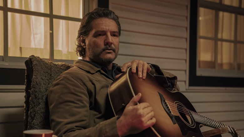 Joel holds his guitar on the balcony on the end