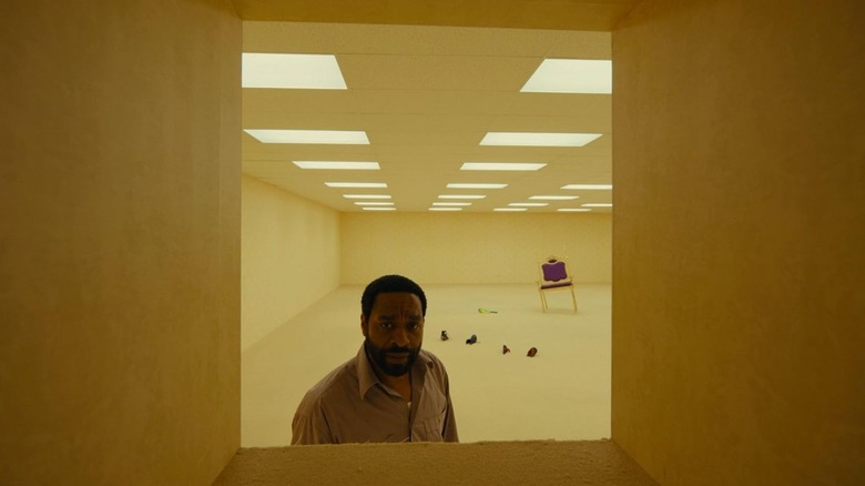 Chiwetel Ejiofor as Clark looking inside of an opening in a yellow room in Backrooms