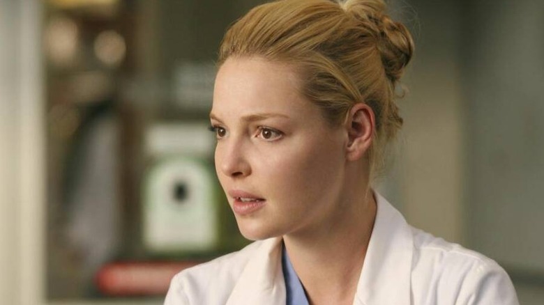Izzie with her hair in a bun and a white coat looking concerned on Grey's Anatomy