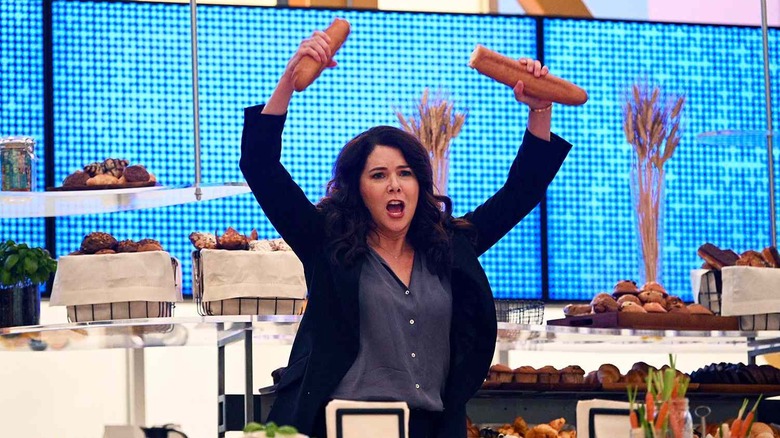 Joan holding two halves of a baguette on Zoey's Extraordinary Playlist