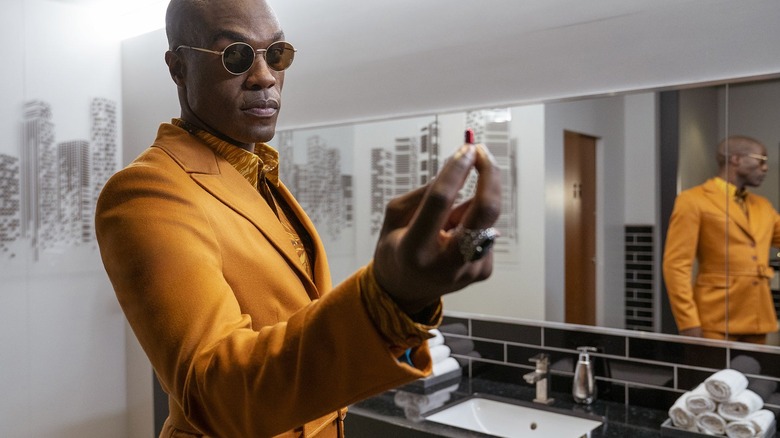Morpheus in a yellow coat holding a red pill in The Matrix Resurrections