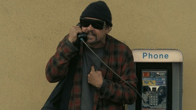 Bob Ferguson, en colère, parlant sur un téléphone public dans One Battle After Another