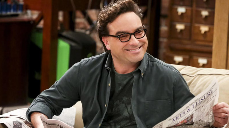 Leonard holding a newspaper and smiling on The Big Bang Theory