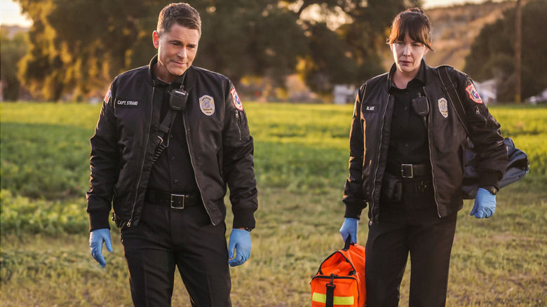 Robe Lowe as Captain Strand standing next to Liv Tyler as Michelle Blake in a field in 9-1-1: Lone Star season 1