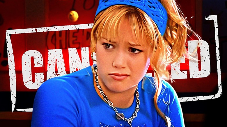 Lizzie McGuire wears a confused and annoyed expression, dressed in a blue shirt, headscarf, and silver chain necklace, with the word 