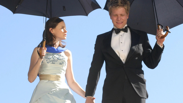 Rory and Logan in formal clothing holding umbrellas and holding hands on Gilmore Girls