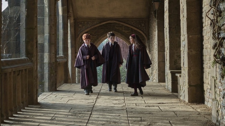Alastair Stout as Ron Weasley, Dominic McLaughlin as Harry Potter, and Arabella Stanton as Hermione Granger walk the grounds of Hogwarts in Harry Potter and the Philosopher's Stone