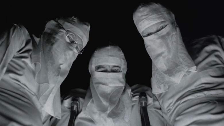 Three doctors in masks from Johnny Got His Gun.