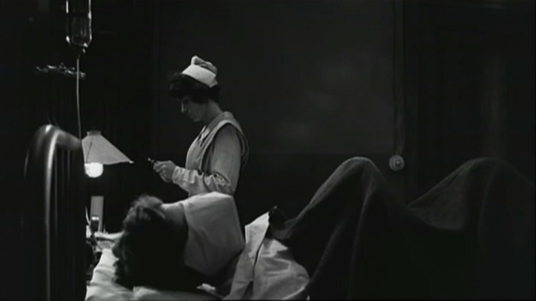 Joe in his bed, a nurse behind him, a scene from Johnny Got His Gun.