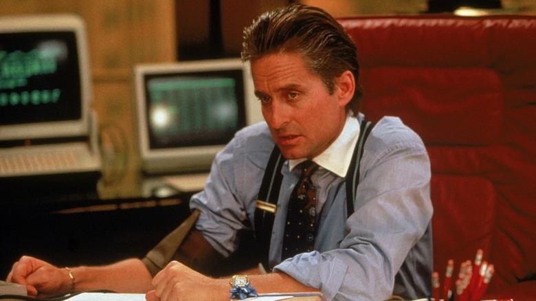 Michael Douglas as Gordon Gekko sits at a desk sporting a pair of power suspenders in Wall Street