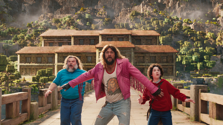 Jack Black as Steve, Jason Momoa as Garrett, and Sebastien Hansen as Henry running across a bridge in A Minecraft Movie