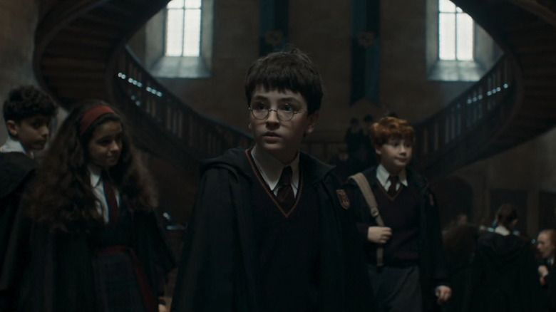 Dominic McLaughlin's Harry Potter stands in a Hogwarts hallway flanked by Alastair Stout's Ron Weasley and Arabella Stanton's Hermione Granger in Harry Potter and The Philosopher's Stone