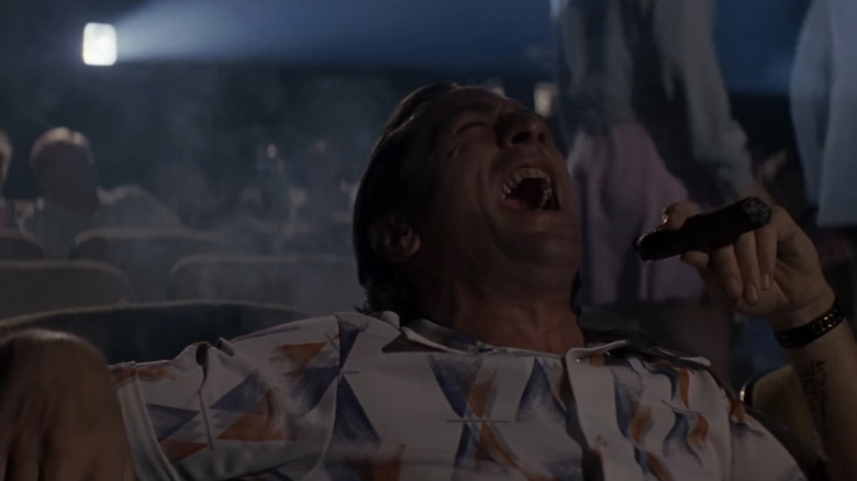 Robert De Niro's Max Cady laughs maniacally as he sits in a movie theater in Cape Fear