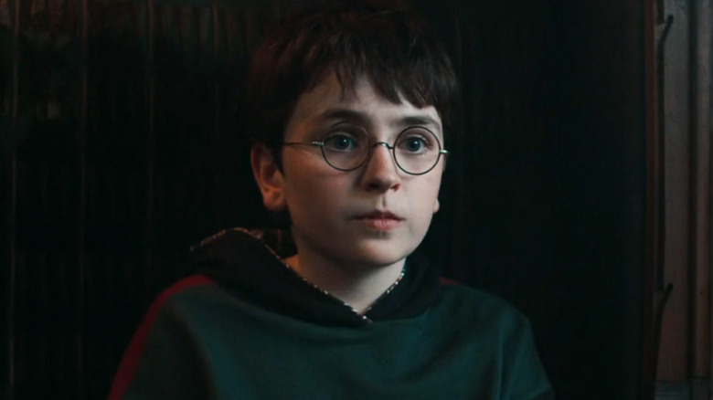 Dominic McLaughlin's Harry Potter sits on a dark bench on a train in Harry Potter and the Philosopher's Stone