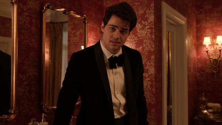 Noah Centineo's Owen stands against a sink in a tuxedo in The Recruit