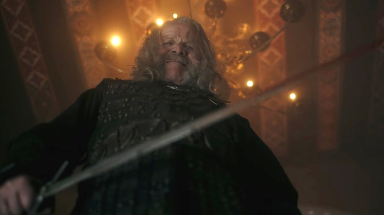 Peter Mullan as Vesemir looking down at the camera with his sword in The Witcher season 4