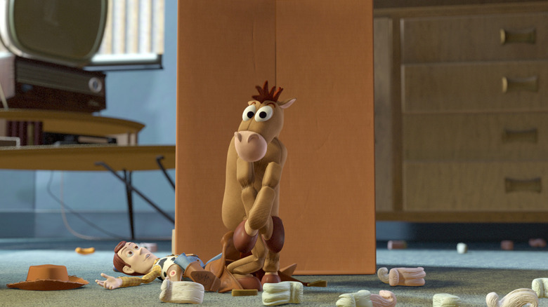 Woody (Tom Hanks) lies on the floor after falling off of Bullseye, who is covering himself out of embarrassment over feeling naked without his saddle in Toy Story 2
