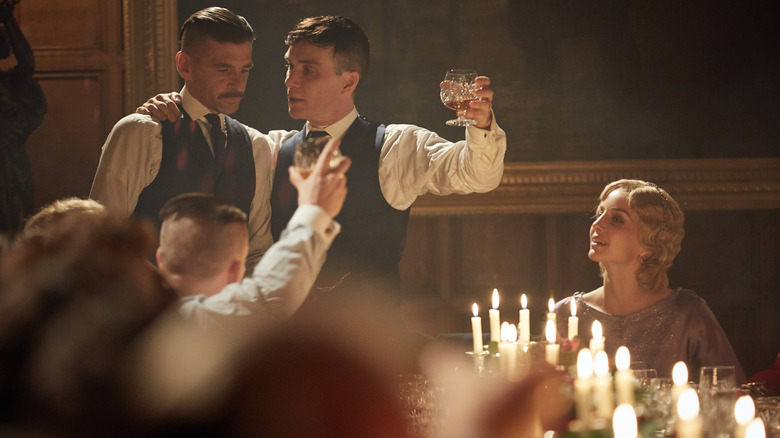 Paul Anderson as Arthur Shelby and Cillian Murphy as Tommy Shelby sharing a toast as Annabelle Wallis as Grace looks on in Peaky Blinders