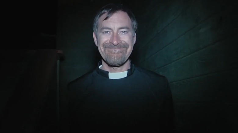 Mark Duplass as Father Tom Durkin standing in the dark in The Creep Tapes