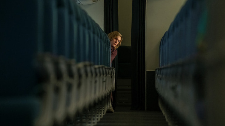 Rhea Seahorn as Carol Sturka peeks out from an airplane seat in Pluribus